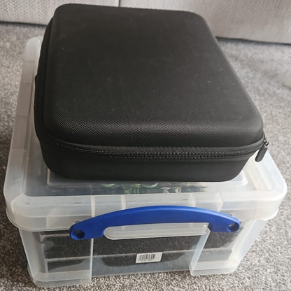 Black zippered case on top of a clear plastic storage box with a blue handle.