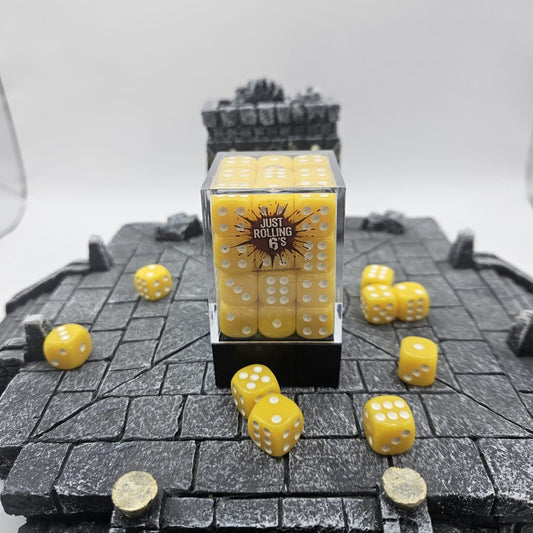 Yellow dice with white pips on a textured surface, with a clear container labeled 'Just Rolling 6's'.